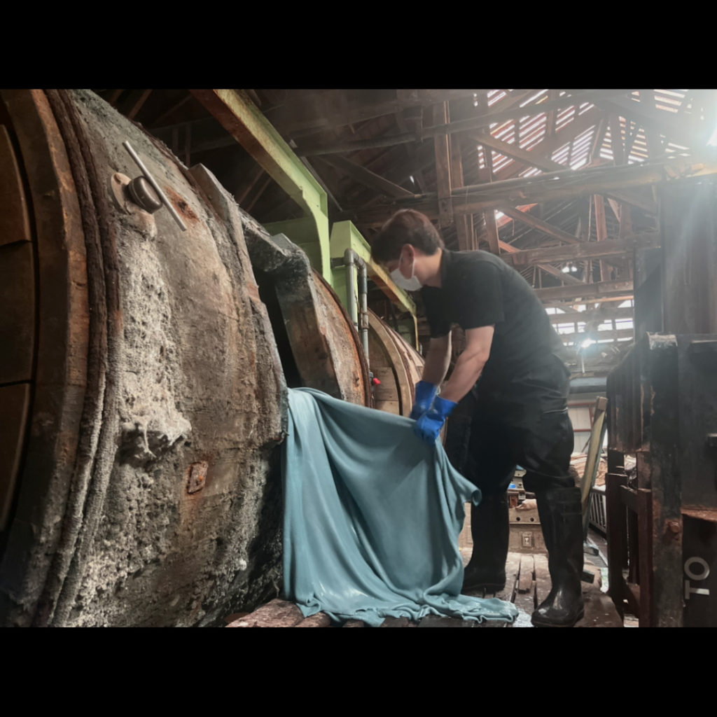 革を作り出す際にとても大切な工程であるクロム鞣しに使うドラムと、革を大切に扱うタンナー職人の様子。